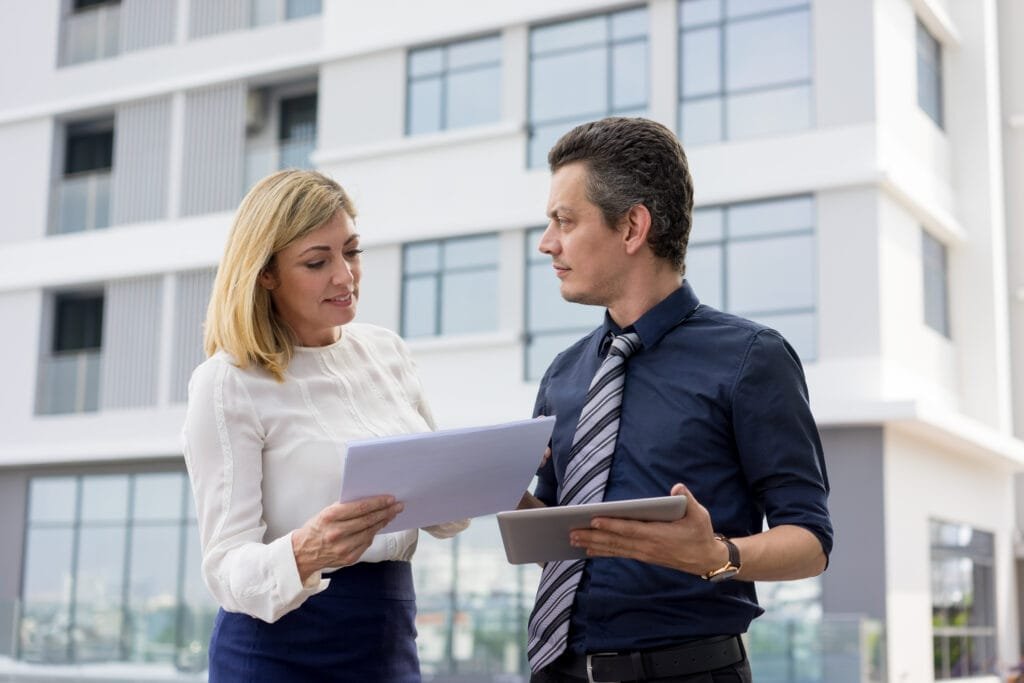 content business partners discussing documents outdoors scaled